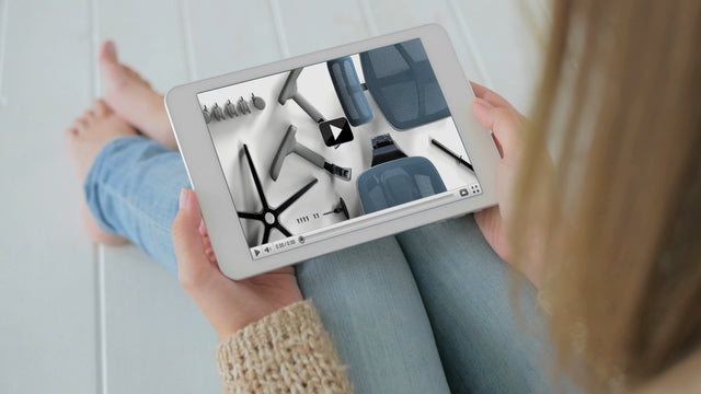 Over the shoulder shot of a woman on her tablet, looking at the Enjoy ergonomic office chair assembly guide video