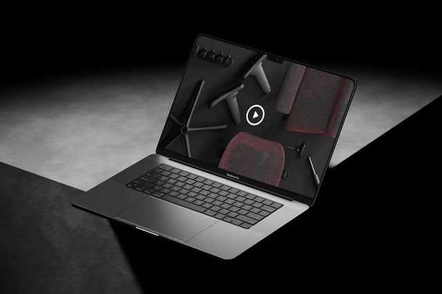 Shot of MacBook Pro on a grey surface with a video of the Mirus Ultra gaming chair assembly guide video open