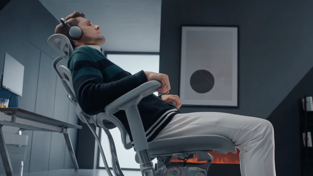 Man wearing headphones reclining on Ergohuman office chair with headrest